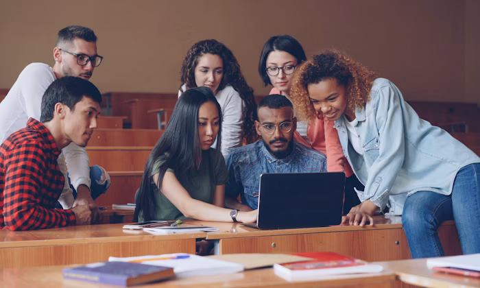 Professor com grupo diverso de crianças aprendendo ao redor de um laptop